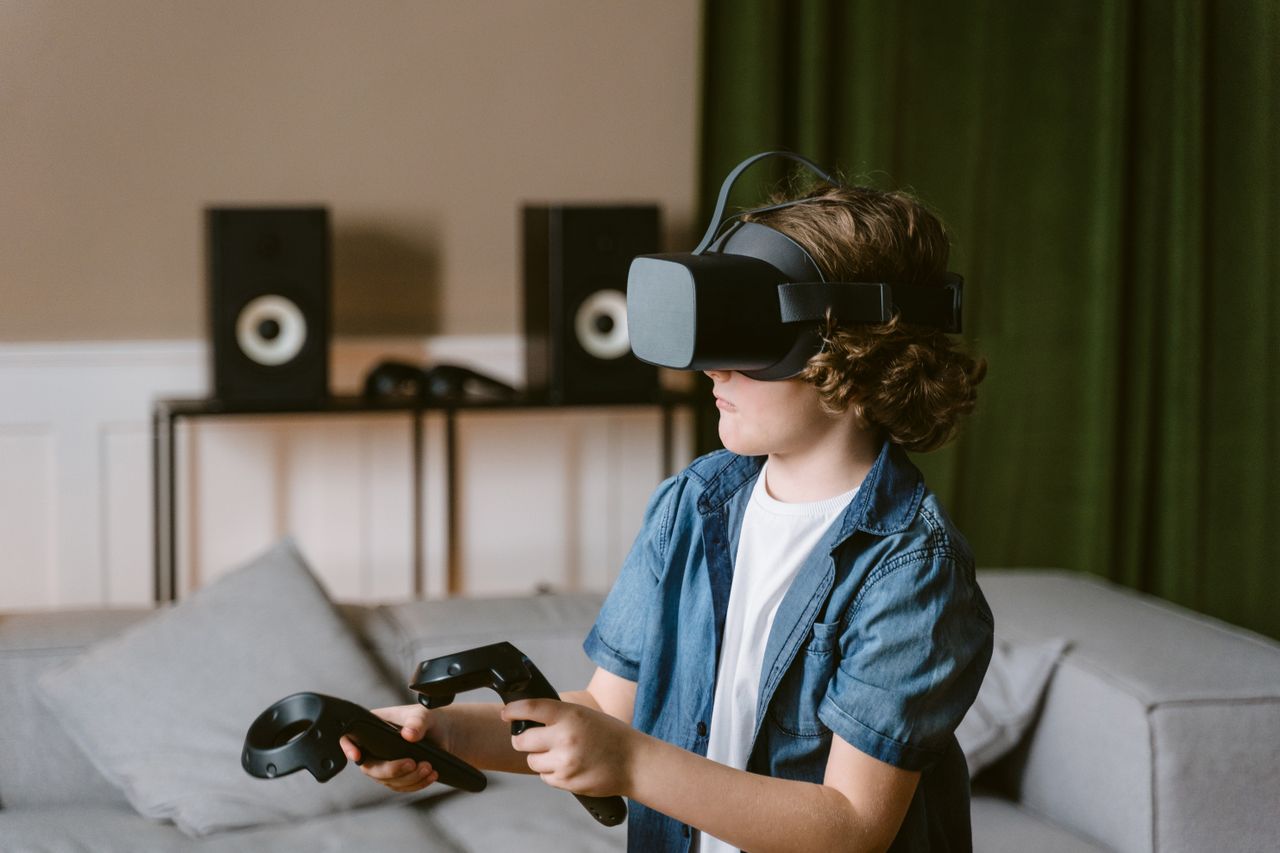 A young boy enjoys a virtual reality experience with a VR headset and controllers indoors.